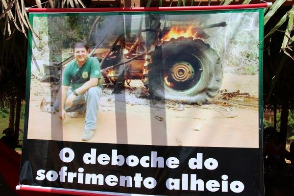 Manifestantes mostram fiscal ambiental ao lado de trator em chamas